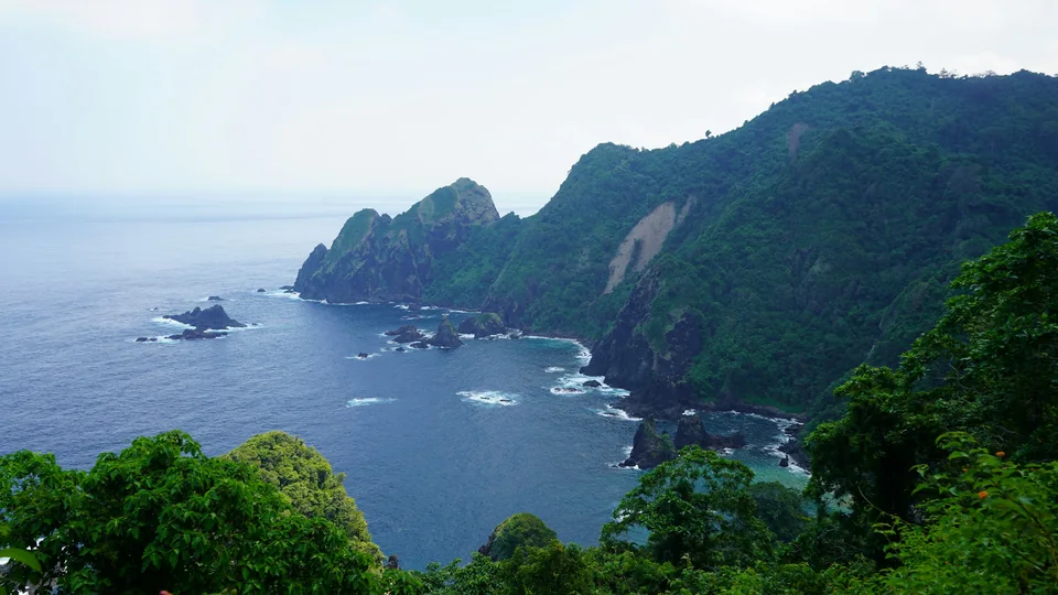 Lush green cliffs above the blue ocean on Lombok’s coastline.